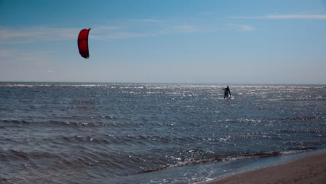 A-kite-surfer-walking-in-shallow-waters-on-its-way-out-in-the-ocean-on-a-hot-summer-day