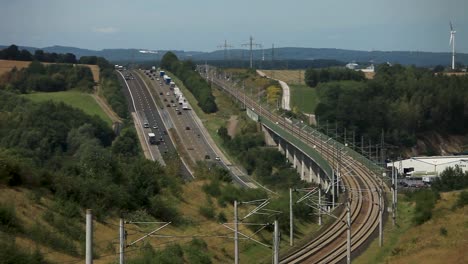 multi-transport route with cars on highway and train on tracks in rural area