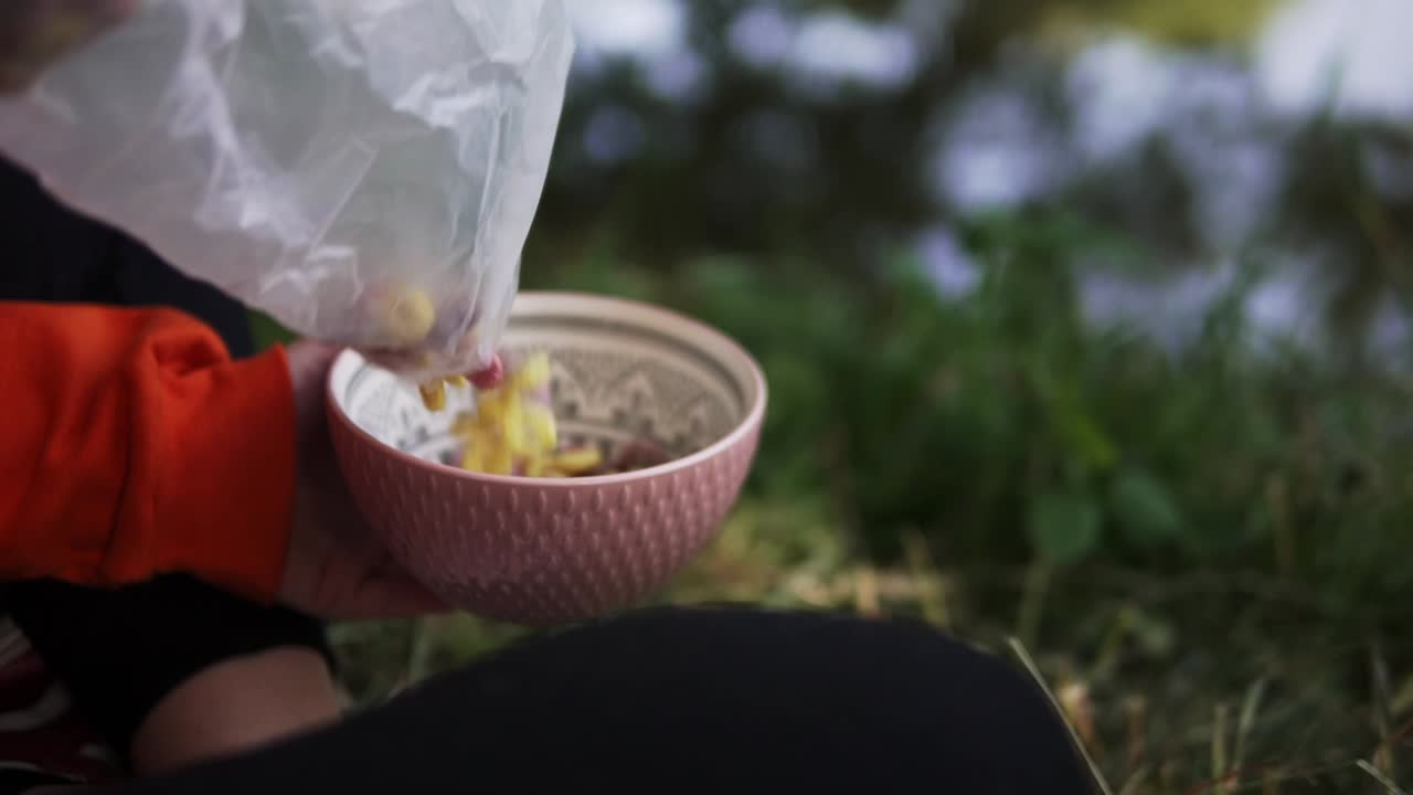 호수 근처 캠핑 여행에서 아침을 먹기 위해 시리얼을 그릇에 채우는 사람