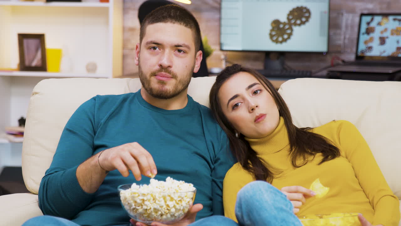Couple watching TV at home with popcorn
