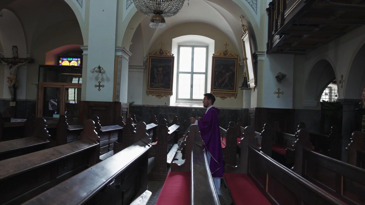 Sacerdote cattolico che porta e agita un turibolo di incenso mentre cammina lungo la navata nella