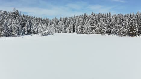 Flying-above-frozen-and-snow-covered-lake-in-winter,-Crno-jezero-or-Black-Lake-on-Pohorje,-Slovenia