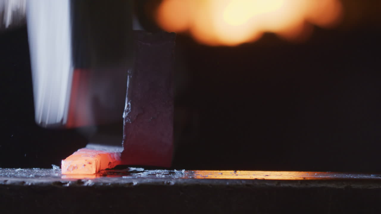 Clanging hammer blows on red-hot malleable metal by smith cause scale to fly off