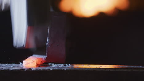 clanging hammer blows on red-hot malleable metal by smith cause scale to fly off