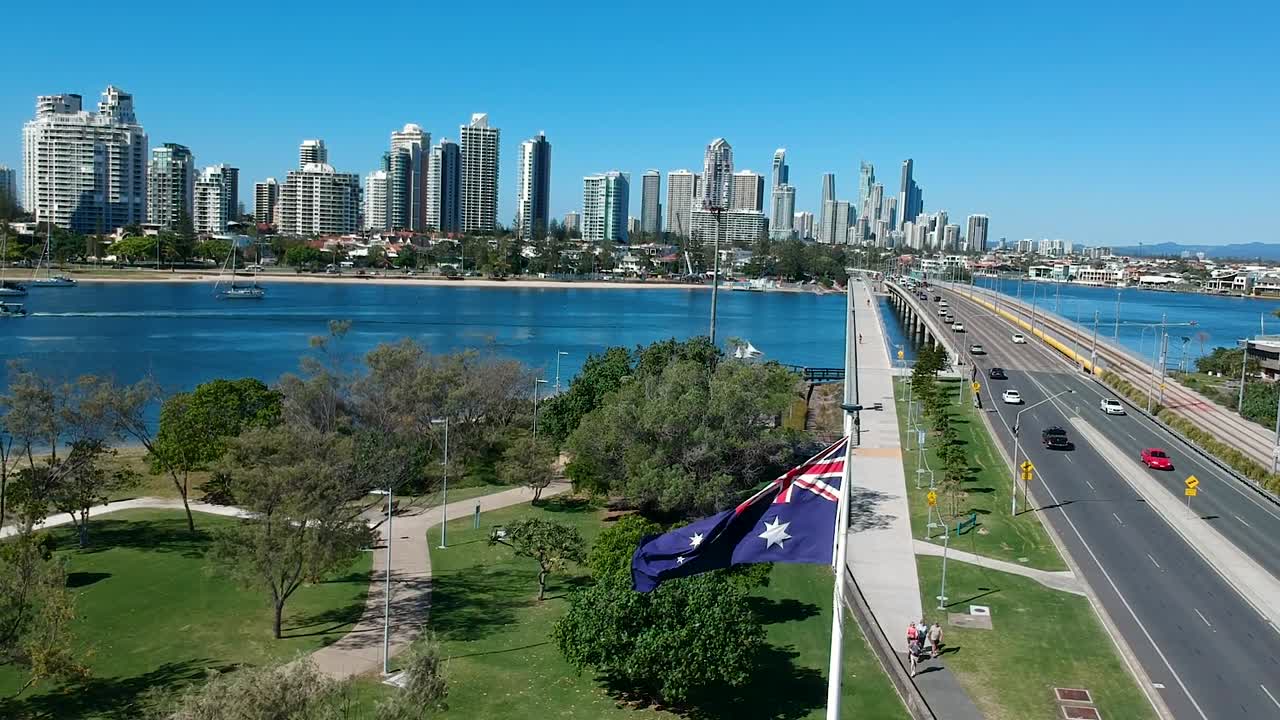 Australische Flagge weht im Wind nahe einem Park und einer Straße