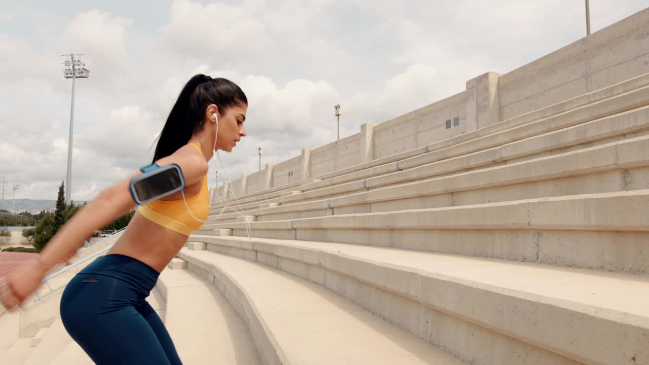 도시 경기장 스탠드에서 점프 스을 하는 건강한 젊은 여성