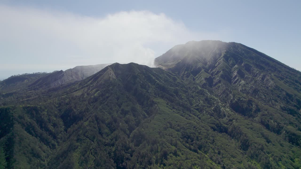 Pemandangan Udara Dekat dari bibir kawah Gunung Ijen yang berasap dengan Danau Toska, dan Pegunungan berkabut di latar belakang - Jawa Timur, Indonesia