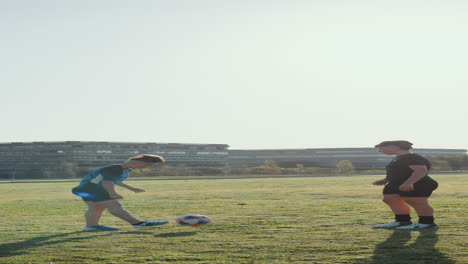 dos mujeres jóvenes haciendo malabarismos y pasando la pelota de fútbol en el campo