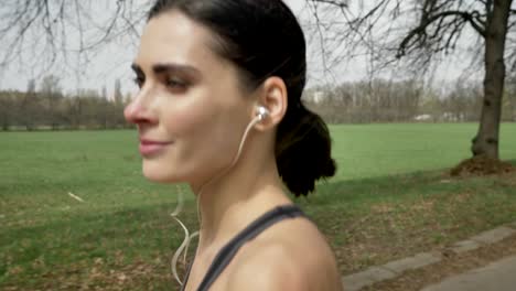 young happy sport girl is running with earphones in park in summer, healthy lifestyle, sport conception, side view