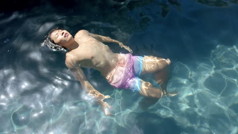 teenage asian boy floats peacefully in clear pool water