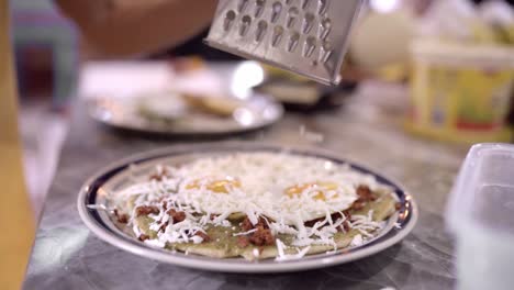 persona irreconocible rallando queso en la comida con huevos y nachos