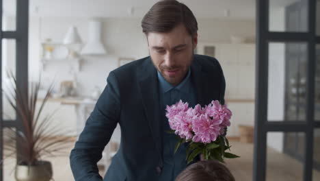 loving man bringing bouquet of flowers to wife at home