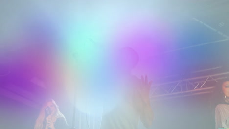 three singers performing on concert stage, with animated microphone icons and glowing light beams