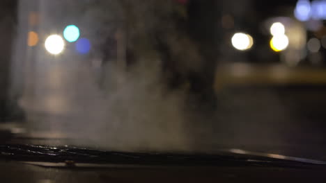 personas caminando por el desagüe humeante en la ciudad nocturna