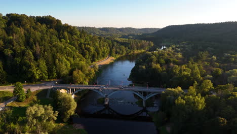 beautiful aerial views of sigulda bridge in latvia. cars crossing over the gauja river surrounded by a spectacular forest valley landscape.