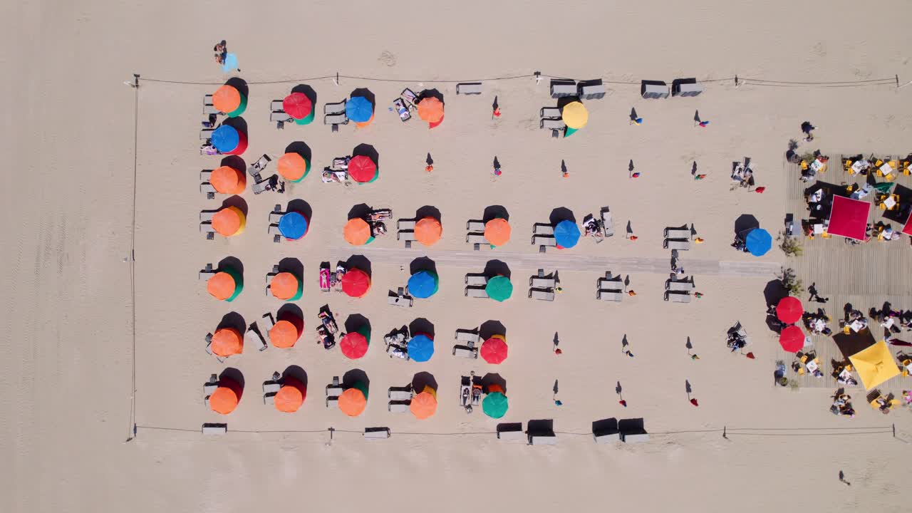 프랑스 노르망디 도빌 해변의 파라솔 아래 관광객들이 있는 여름 휴양지