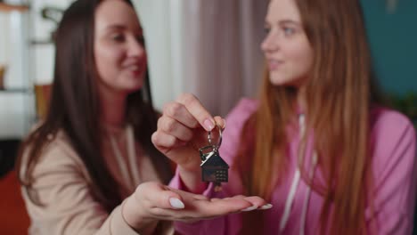 Girls-siblings-homeowners-hugging-and-showing-new-home-apartment-keys,-receiving-mortgage-loan