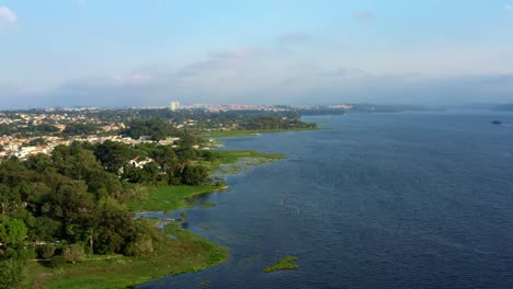 beautiful rotating aerial drone shot of the man-made guarapiranga reservoir in the south part of são paulo, brazil with beaches, marinas, natural green ecosystems, and wildlife on a fall evening