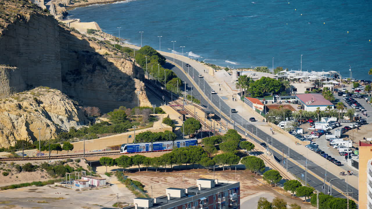 Alicante, Spain - May 20, 2025: Tram hugging the coastline beneath Serra Grossa, near Sangueta stop