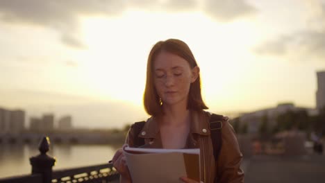 cute ginger girl sketching and walking in city at sunset