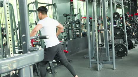 A man performs tricep exercises on a cable machine in a well-lit gym environment