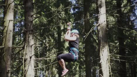 Young-woman-in-protective-helmet-and-belt-moving-on-rope-in-climbing-park