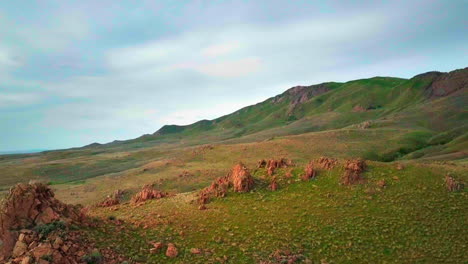 A-beautiful-drone-shot-passing-a-rocky-mountainous-range-with-green-plants