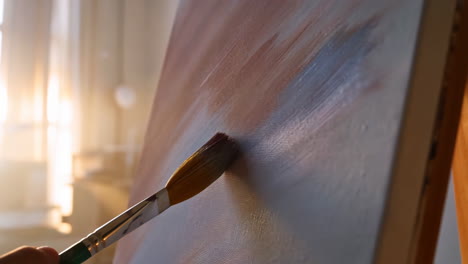 artist painting on canvas in studio