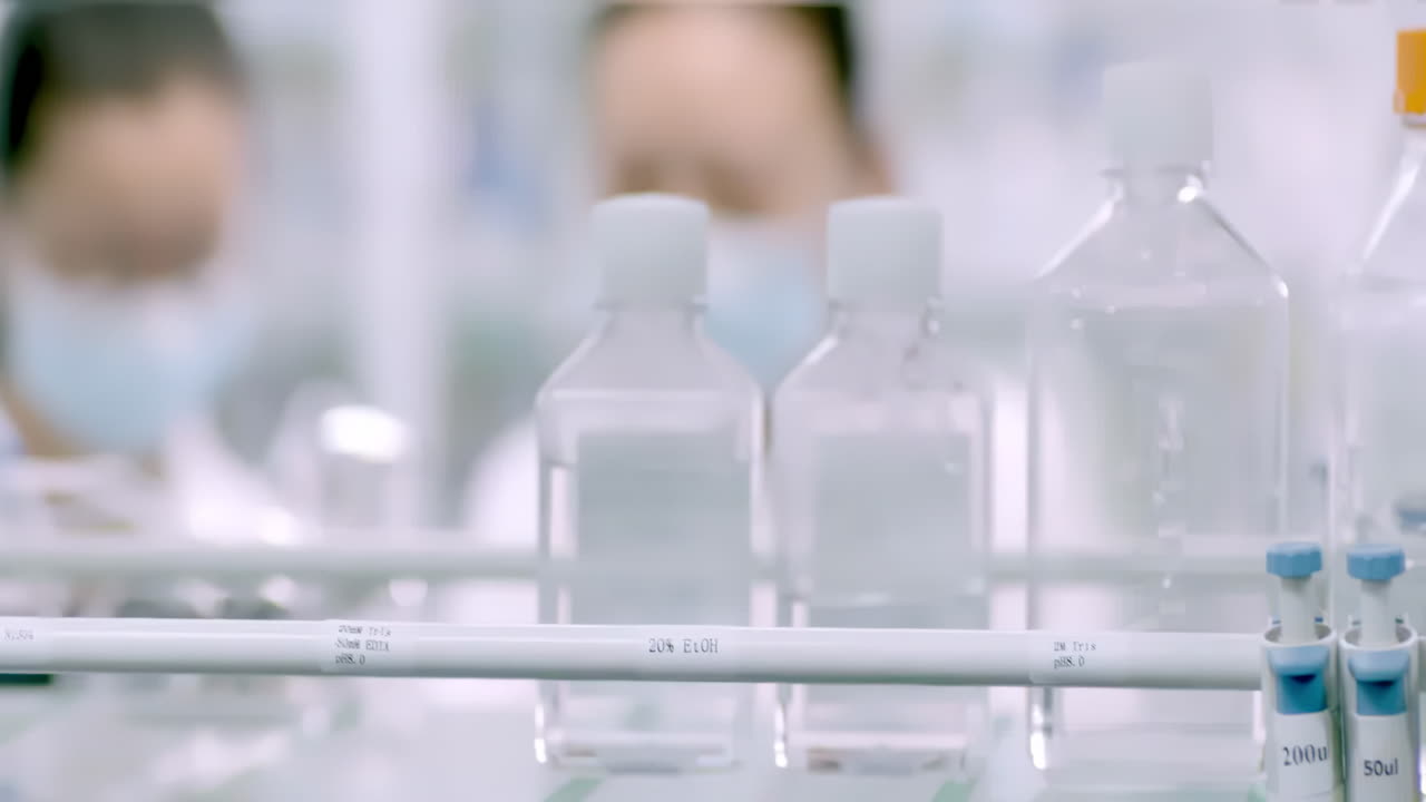 Biotechnology scientists or researchers working together in biological laboratory, carrying out experiments and analyzing their findings while using microscope and test tubes