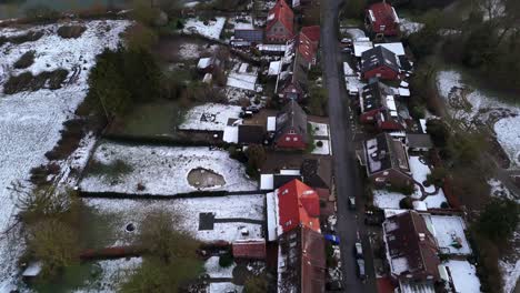 straight street of housing area with snowy garden near lake in winter season. aerial top down flyover shot. cloudy day in american suburb neighborhood.