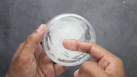 clear slime in a plastic container being touched by fingers