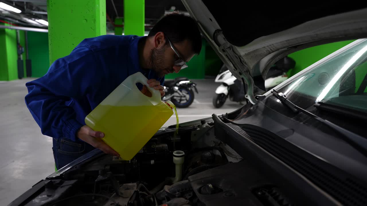 hombre torpe llenando el tubo del limpiaparabrisas en el garaje, 4k