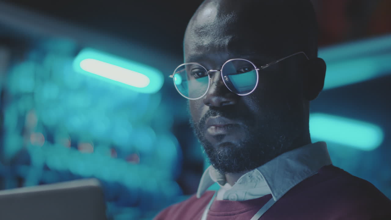 A man in glasses looks at a screen in a server room
