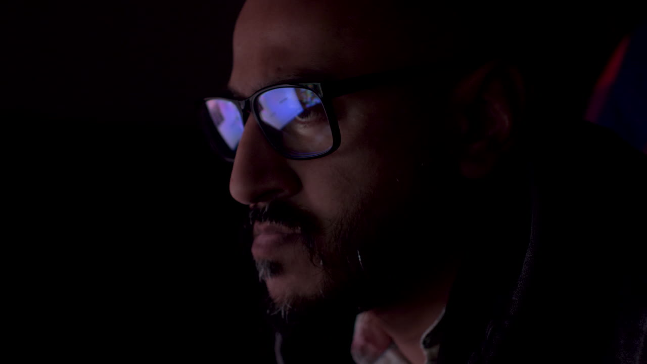 hombre serio con reflejo de la pantalla del portátil con datos del sitio web en gafas trabajando hasta tarde, de cerca