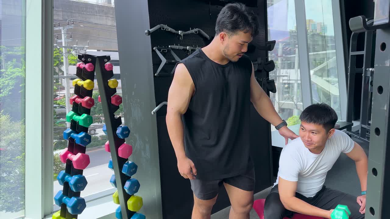 Trainer supervises client lifting dumbbell in modern gym, natural daylight, supportive atmosphere, close-up view