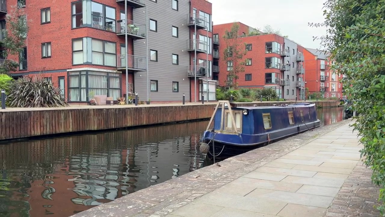 Manchester Kanal med blå smalbåd, vandkant i røde mursten og byvandresti