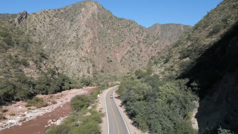 vista aérea de un automóvil que viaja en el terreno montañoso salvaje de los andes de argentina, carretera de asfalto y autopista