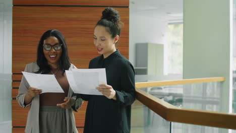 multiethnic female colleagues discussing documents