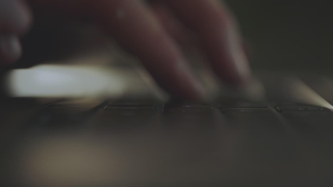primer plano de las manos escribiendo en un teclado de portátil por la noche