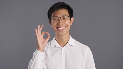 asian man smiling and doing ok gesture to the camera.