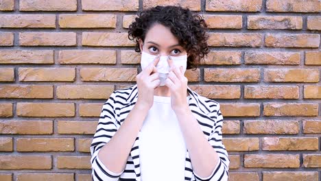 brunette woman shows step by step how to put on mask to avoid contamination by sars-cov-2 coronavirus