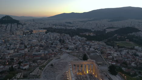 toma aérea inclinada hacia arriba de la acrópolis y la ciudad de atenas durante el amanecer