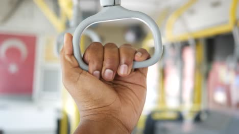 closeup of a hand holding a bus handle