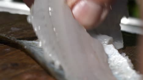cuchillo de filete preparando pescado de carne blanca en primer plano, cocina de verano al aire libre
