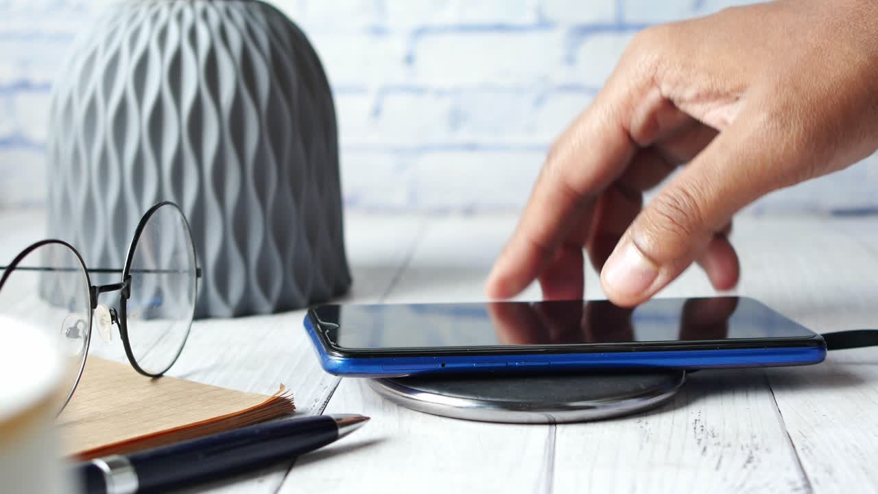 mano colocando un teléfono móvil en un cargador inalámbrico