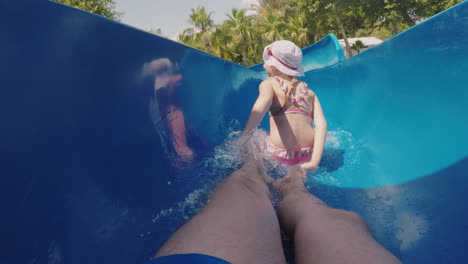 A-Happy-Family-With-A-Child-Is-Riding-A-Water-Slide-Laughing-Waving-Their-Hands-At-The-Camera-Slow-M