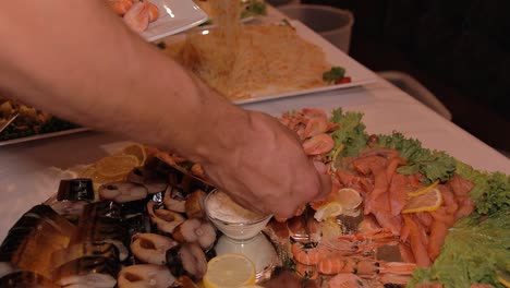 a man chooses and puts on a plate shrimp from the buffet