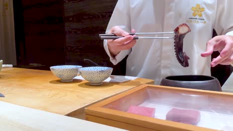 chef skillfully prepares octopus sushi in bangkok