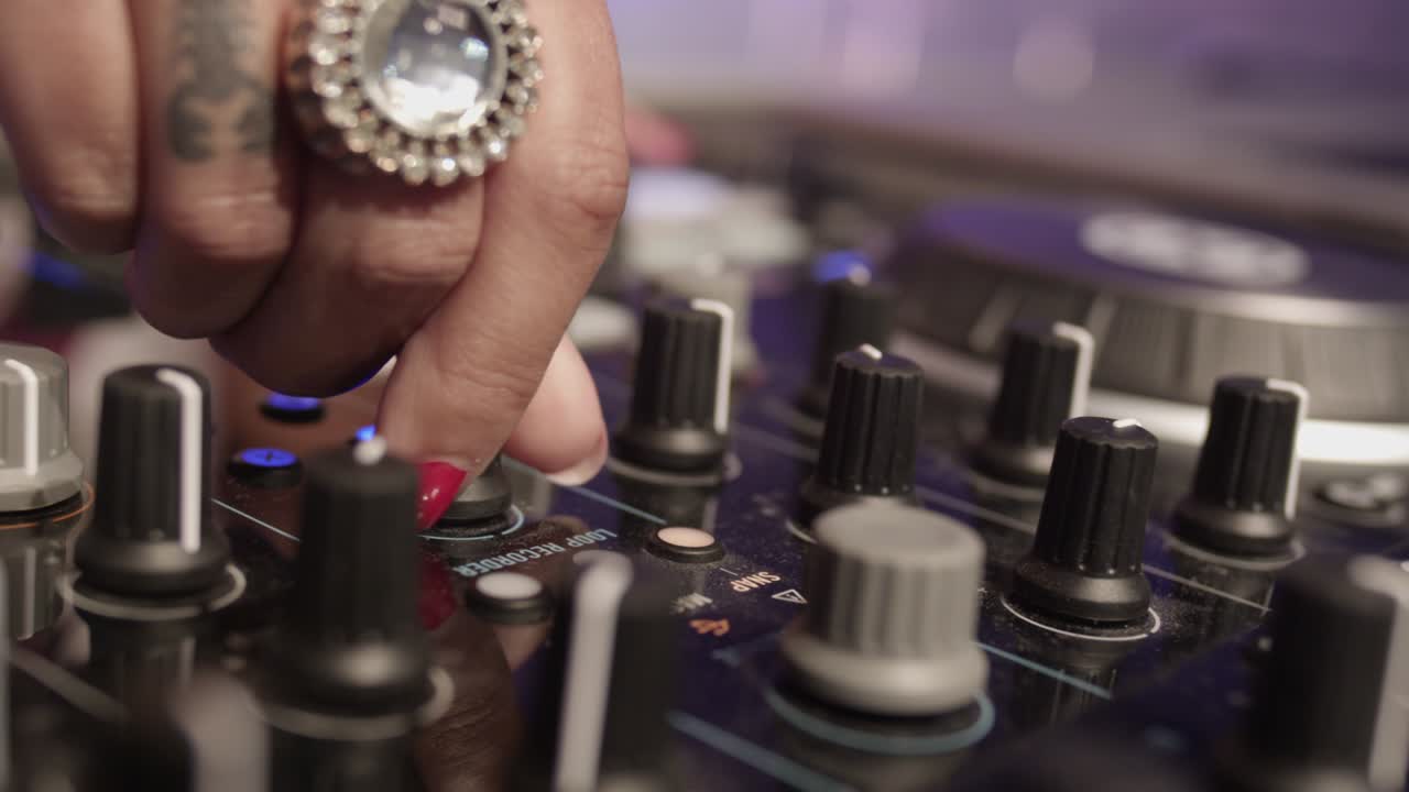 mano femenina con esmalte de uñas rojo sintonizando un mezclador giratorio