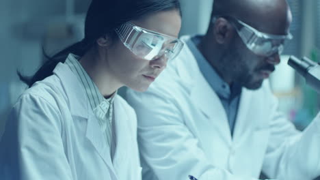 black chemist doing laboratory research with female assistant taking notes
